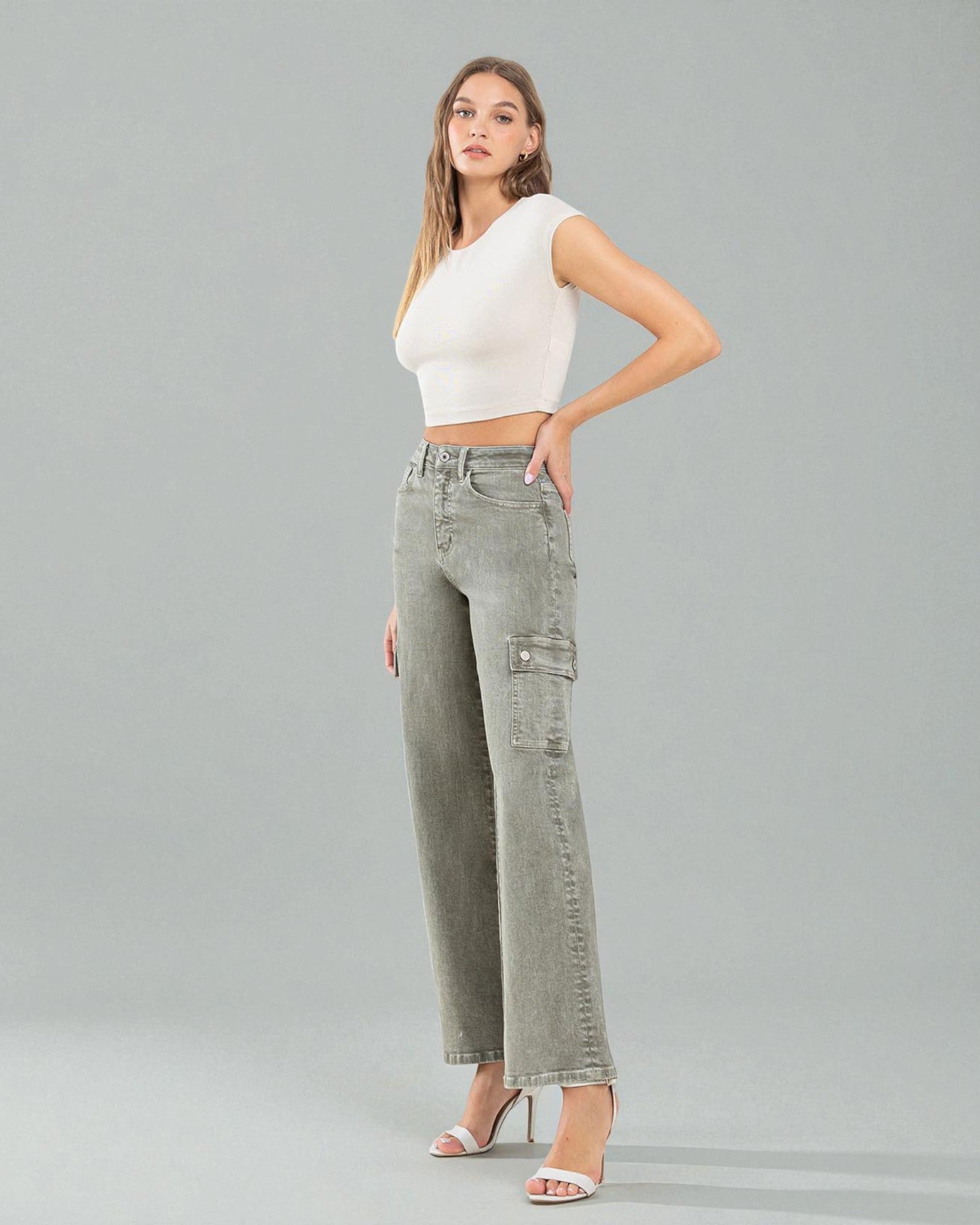 Woman wearing a white top and gray cargo pants on a gray background