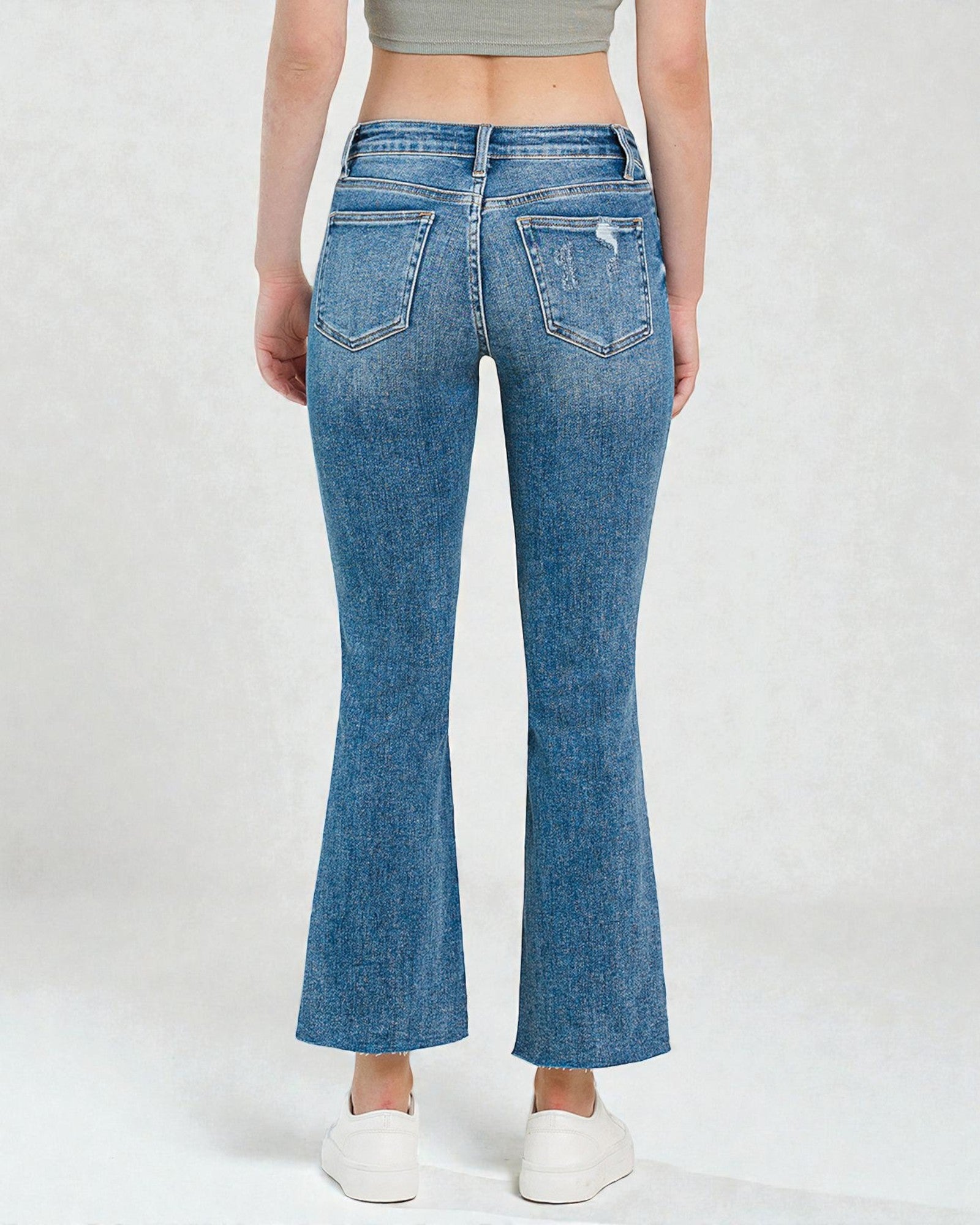 Person wearing blue flared jeans on a white background