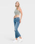 A woman modeling a light gray ribbed crop top and blue cropped flare jeans with distressed knees, paired with white sneakers, against a light gray studio background.