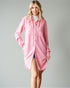 Woman wearing a pink shirt dress against a gray background