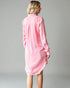 Woman wearing a pink shirt dress against a gray background