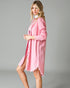 Woman wearing a pink shirt dress against a gray background