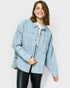Woman wearing a light blue denim jacket on a white background