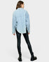 Person wearing a light blue patterned shirt and black pants on a white background
