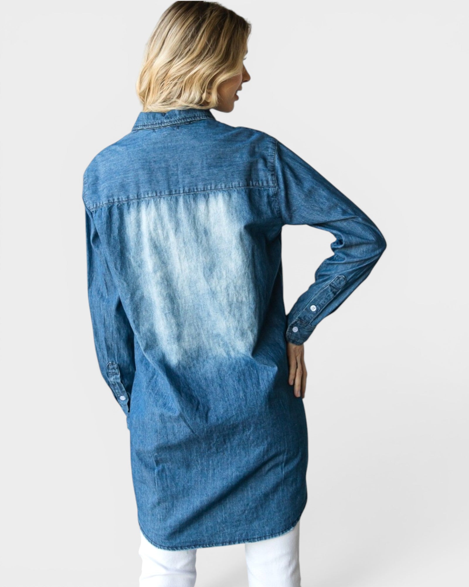 Woman wearing a long blue denim shirt on a white background