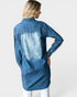 Woman wearing a long blue denim shirt on a white background