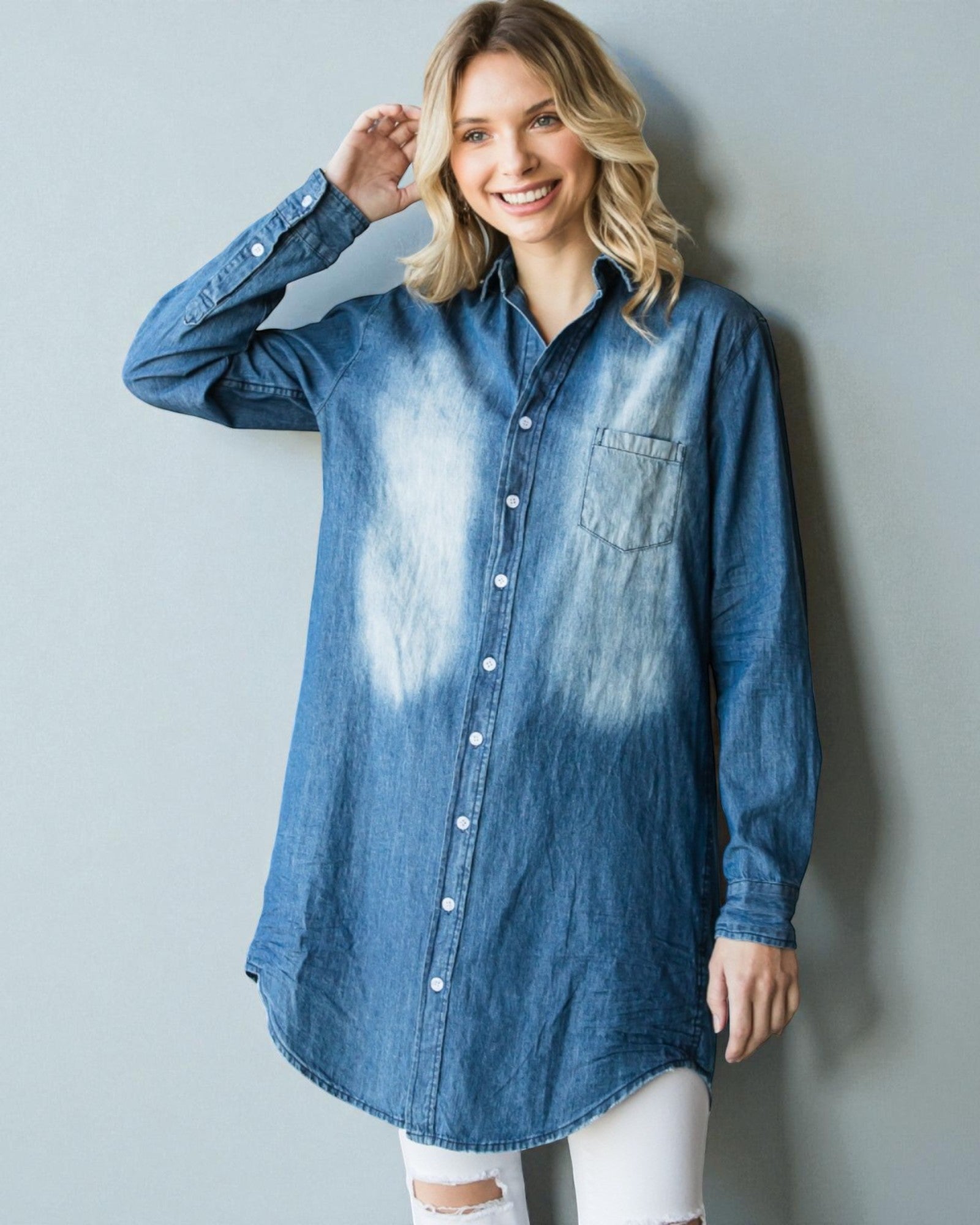 Woman wearing a blue denim shirt with a white wall background
