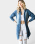 Woman wearing a long denim shirt over a white top and jeans on a white background
