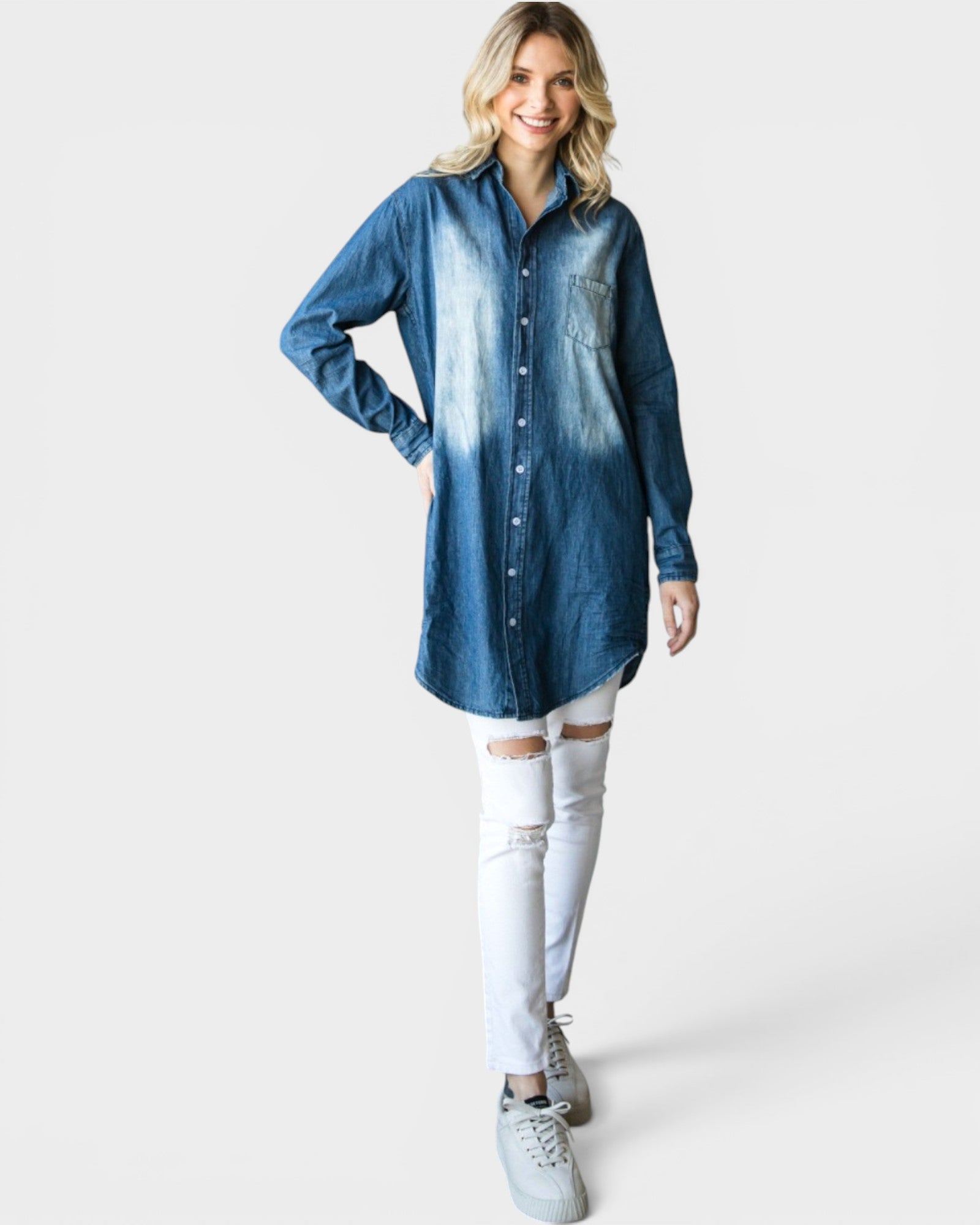Woman wearing a long blue denim shirt and white pants on a white background