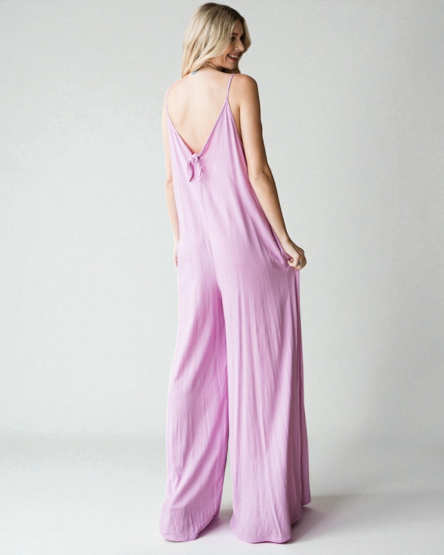 Woman wearing a pink jumpsuit on a plain background