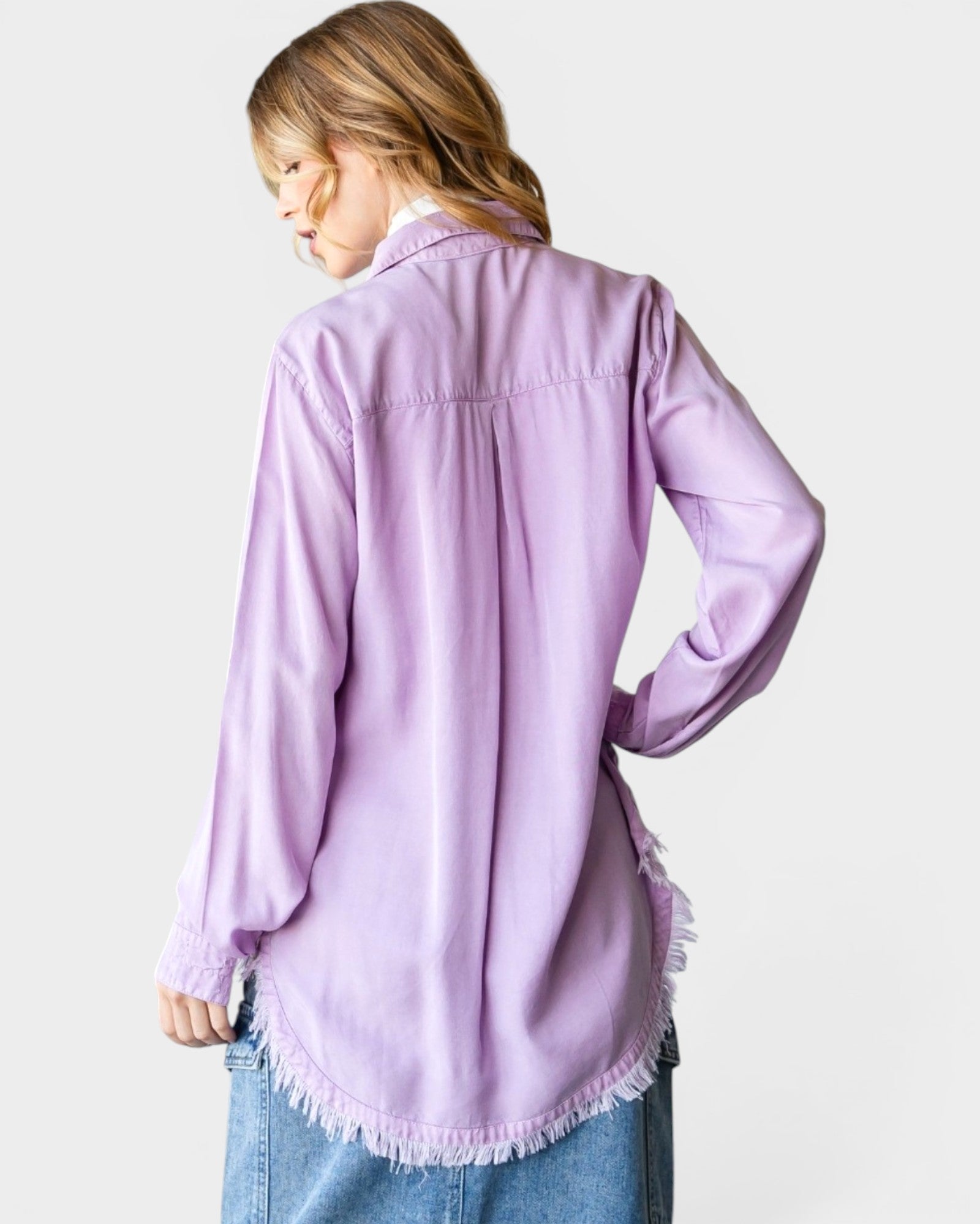 Person wearing a light purple shirt with frayed hem on a white background