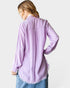 Person wearing a light purple shirt with frayed hem on a white background