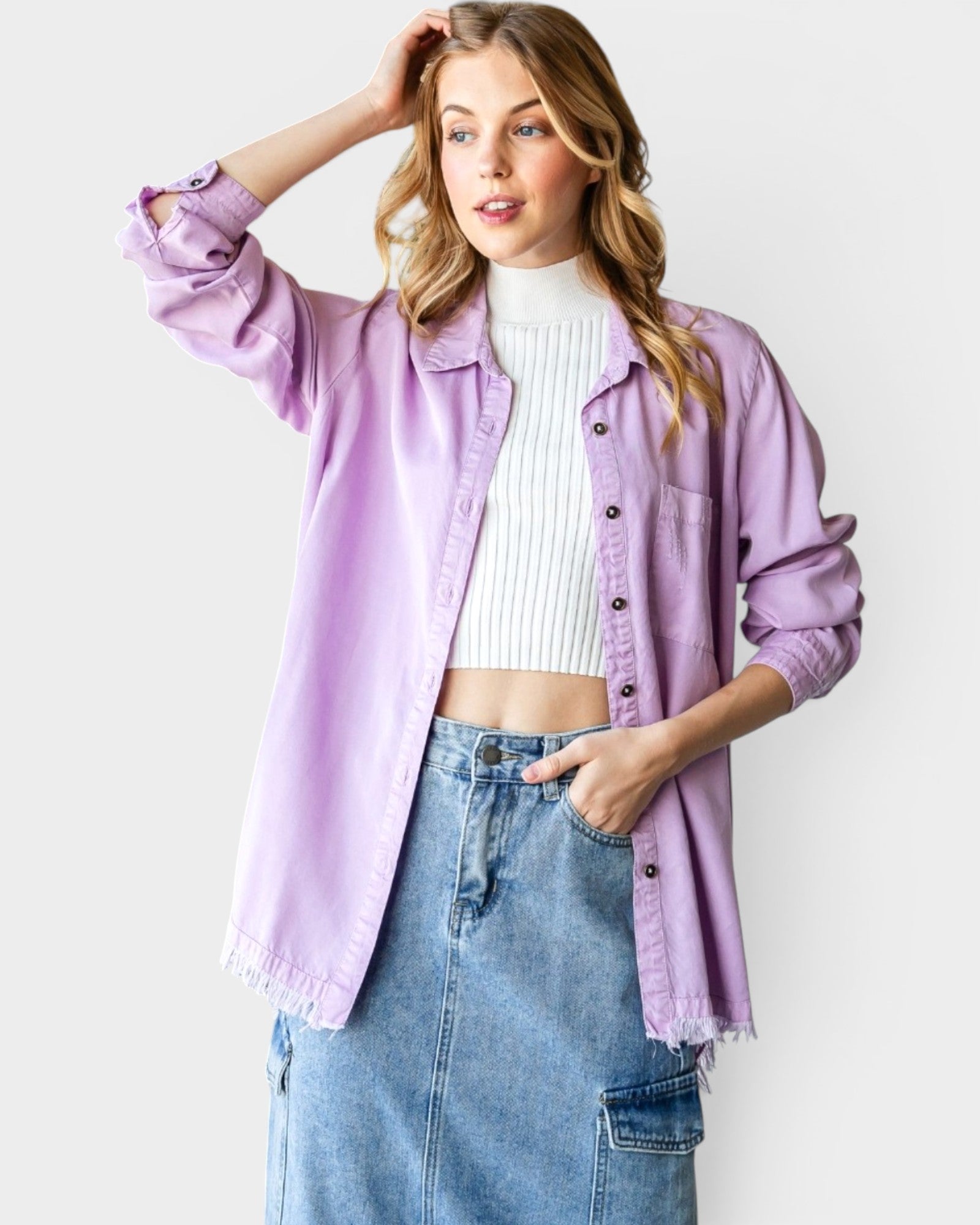 Woman wearing a light purple jacket over a white top and blue jeans on a white background