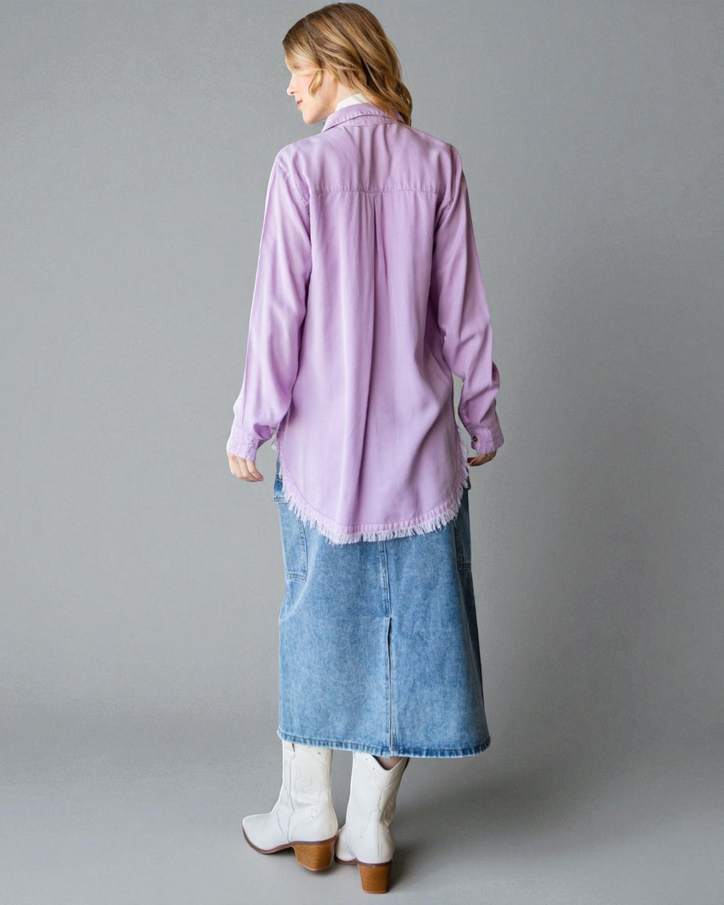 Woman wearing a light purple shirt and blue denim skirt on a gray background