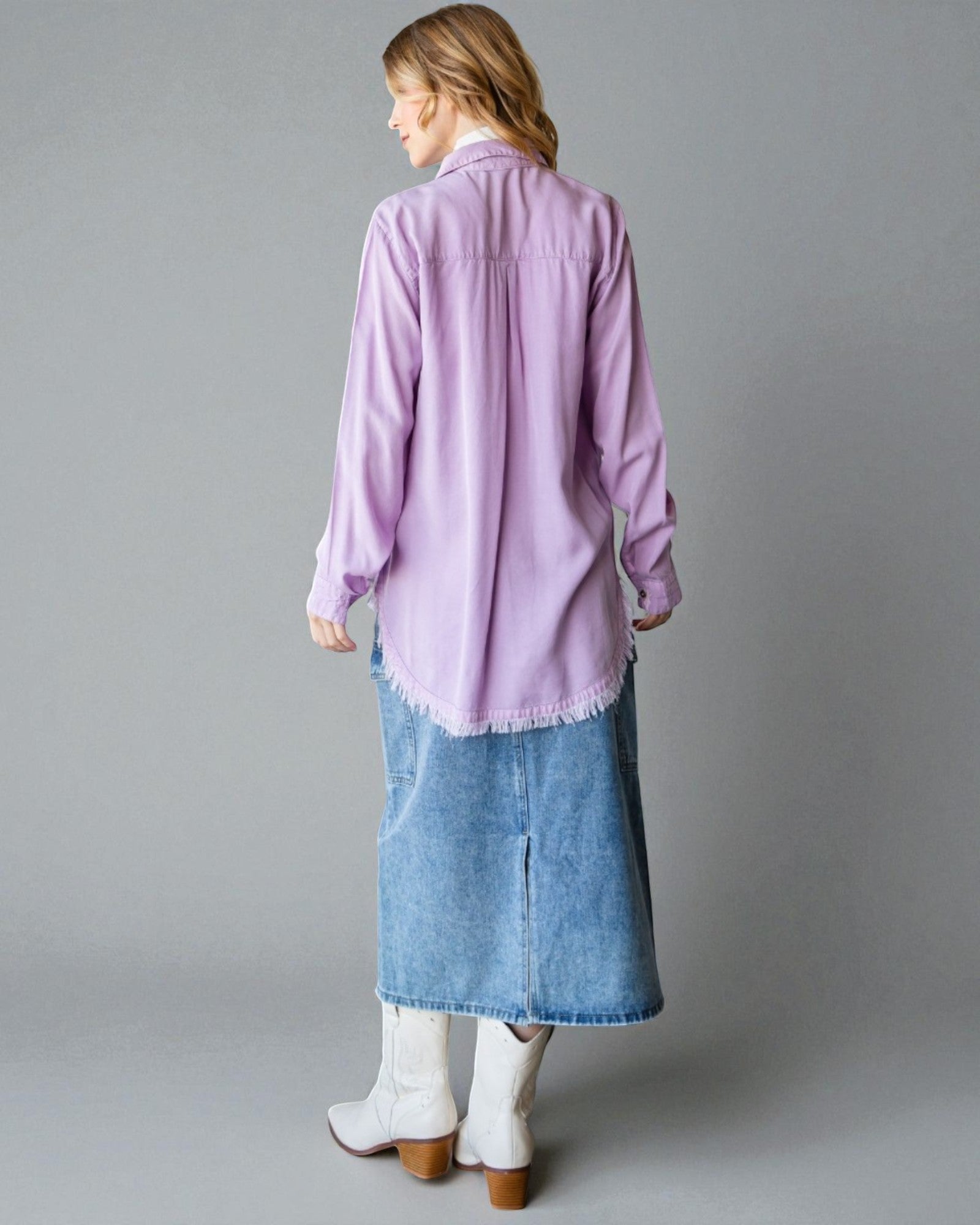 Woman wearing a light purple shirt and blue denim skirt on a gray background