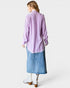 Woman wearing a light purple shirt and blue denim skirt on a white background