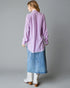 Woman wearing a light purple shirt and blue denim skirt on a gray background