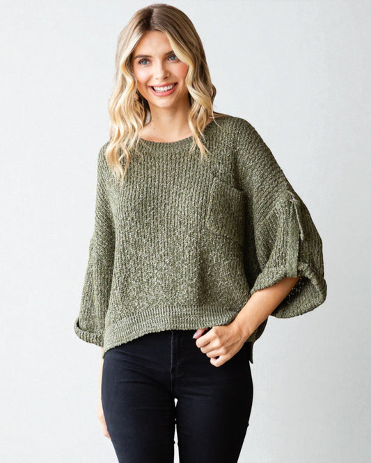 Woman wearing a green sweater with bell sleeves against a white background