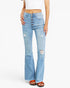 A model wearing light-wash blue high-rise flare jeans with a five-button front closure, distressed details on the thighs and knees, and a raw frayed hem, paired with a white crop top and brown sandals.