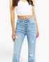 A model wearing high-waisted, light blue distressed jeans with a prominent five-button fly, paired with a white crop top against a plain white background.