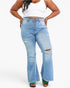 A model wearing light-wash blue distressed flare jeans with a button-fly front, paired with a white crop top and green sandals, against a plain white background.