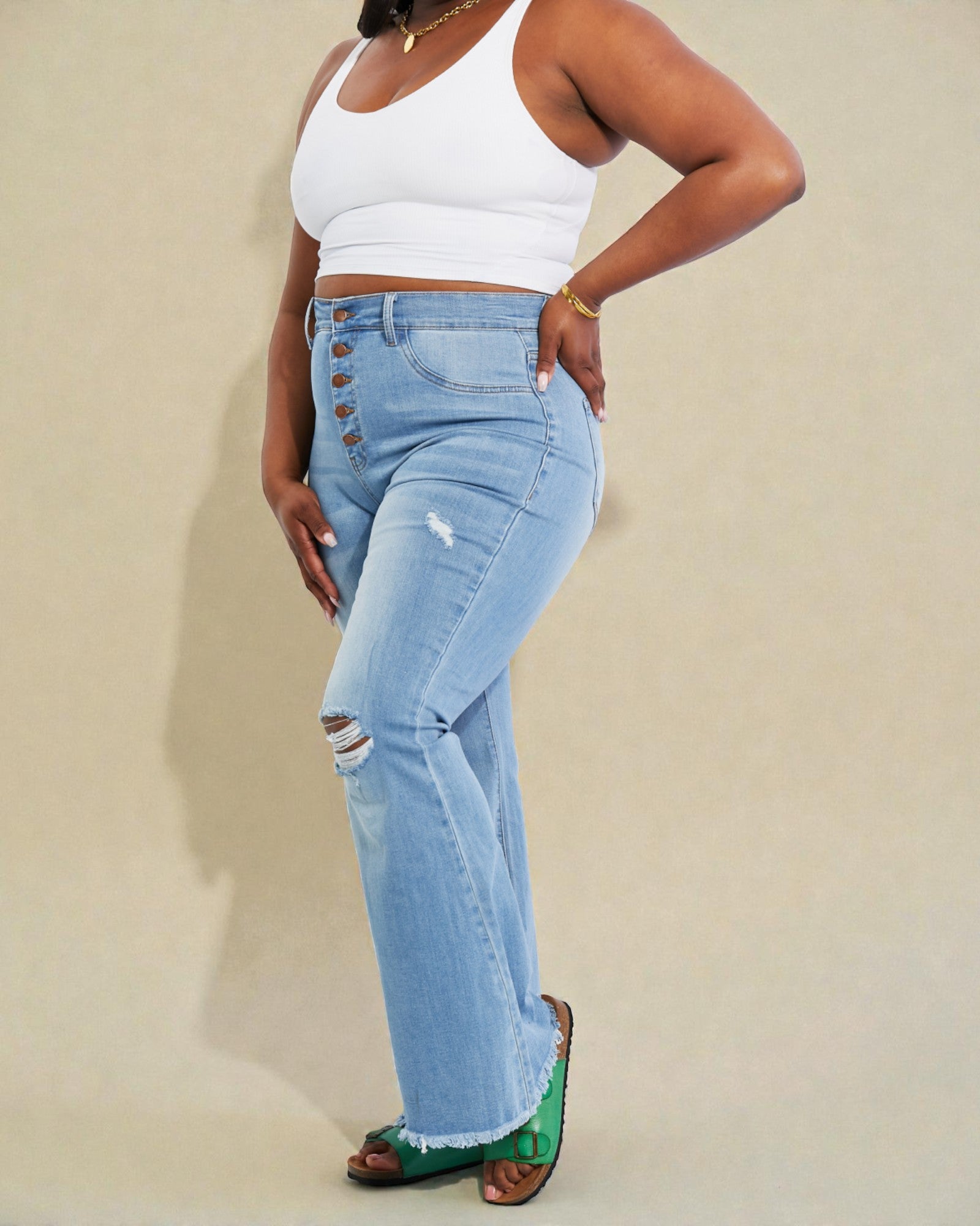 Person wearing light blue jeans with a white top on a beige background