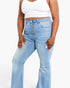A model wearing high-waisted, light blue flare jeans with a distinctive front button closure, paired with a white crop top against a plain white background.