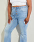 Person wearing light blue jeans and a white top against a neutral background