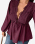 A close-up of a woman wearing a deep burgundy long-sleeve blouse with a lace-trimmed plunging neckline and a drawstring waist, paired with blue jeans against a plain white background.