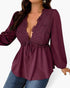 A woman wearing a long-sleeve deep burgundy blouse with a lace V-neck bodice, tie waist, and gathered peplum hem, paired with blue jeans against a light gray background.