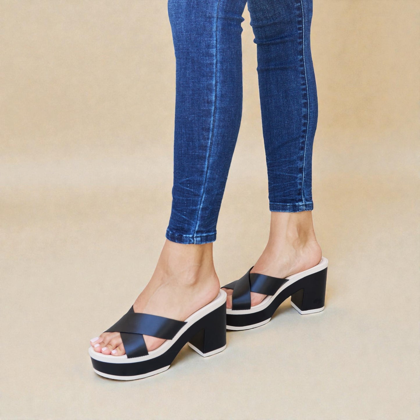 Navy platform sandals worn with blue jeans on a beige background