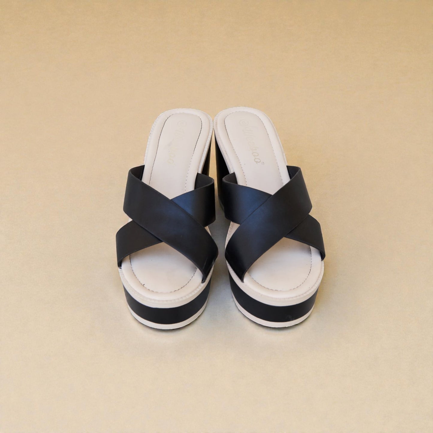 Pair of black and white sandals on a beige background
