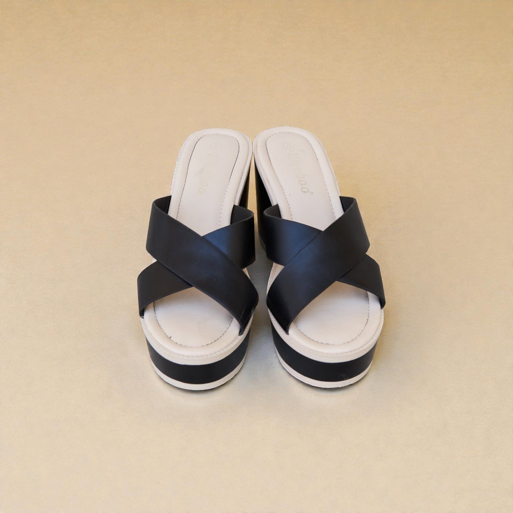Pair of black and white sandals on a beige background