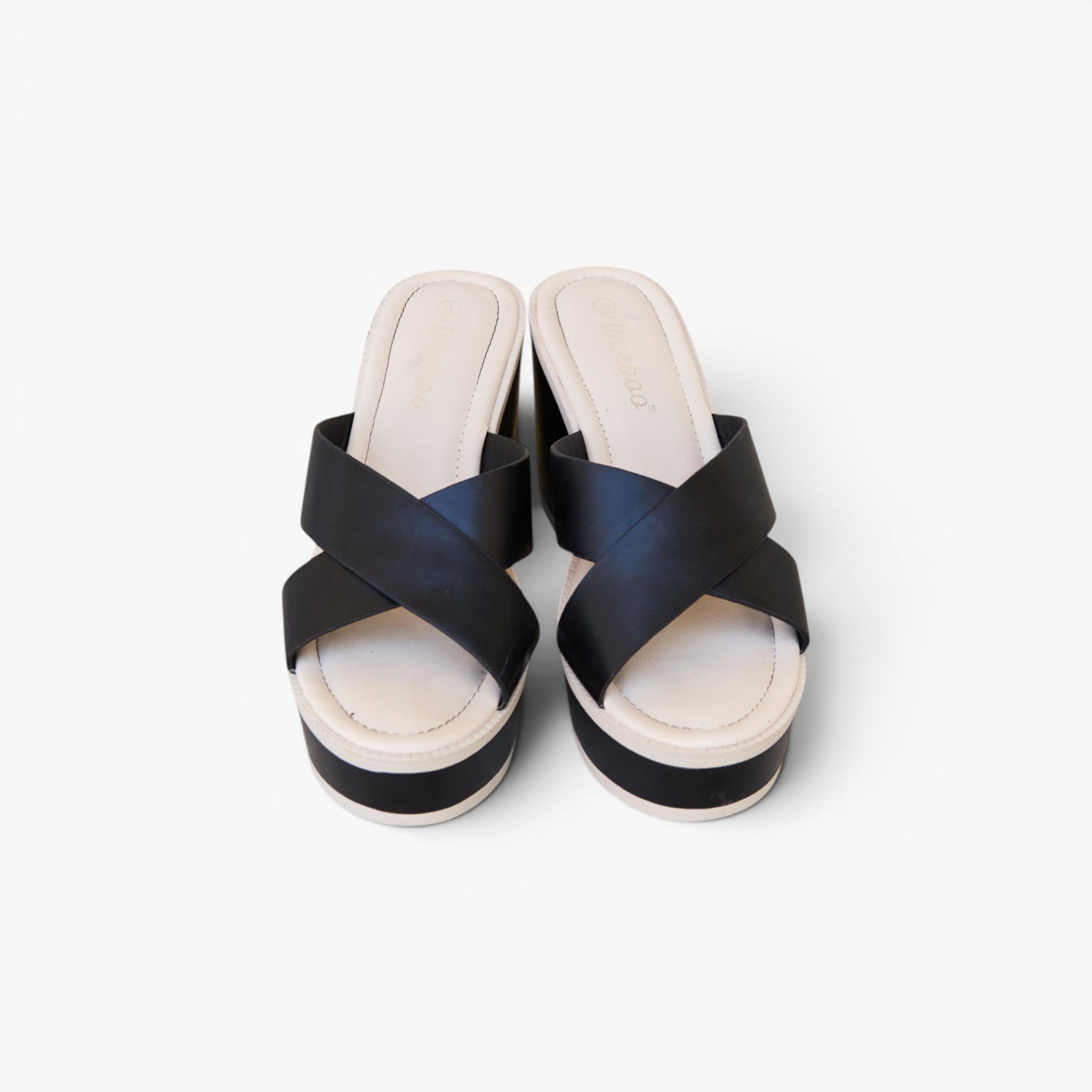 A pair of women's platform slide sandals with wide black crisscross straps and a thick cream-colored platform sole, shown from a top-down view on a light gray background.