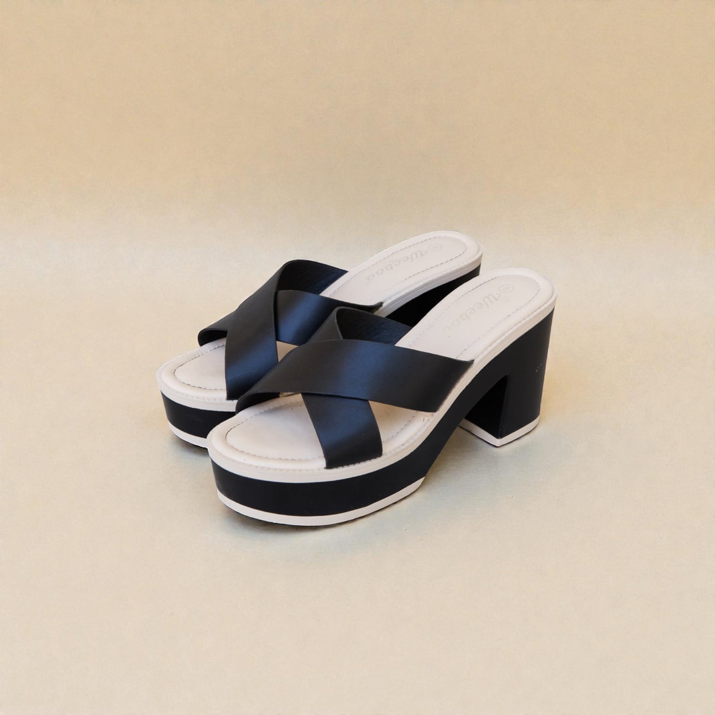 Black and white platform sandals on a beige background
