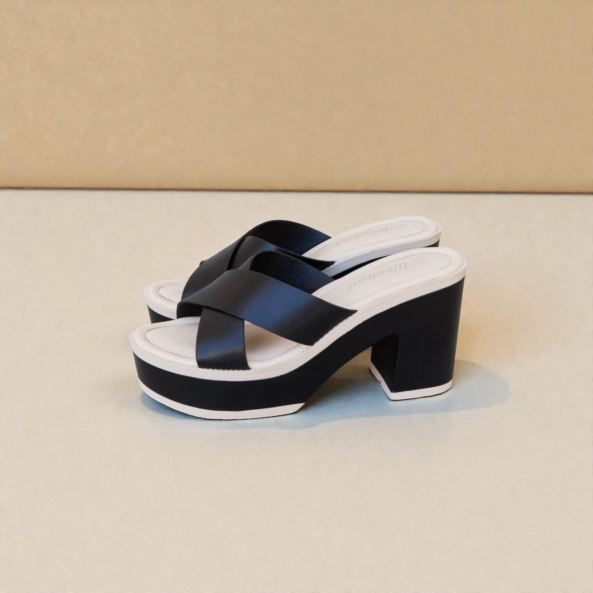 Black platform sandals with white sole on a beige background