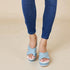 Blue sandals worn with blue jeans on a beige background
