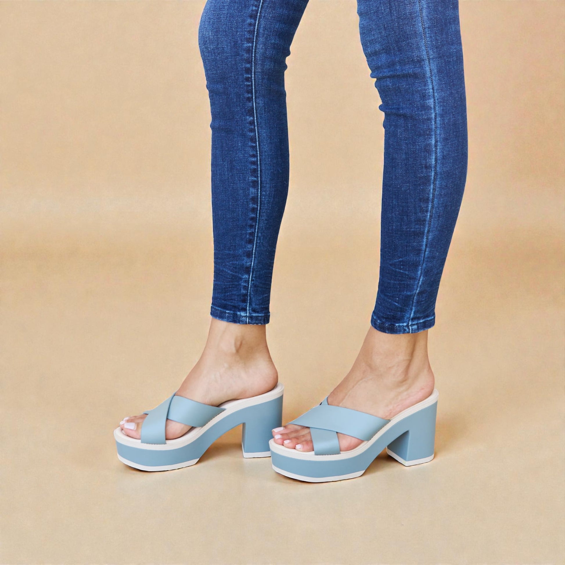 Blue platform sandals worn with blue jeans on a beige background