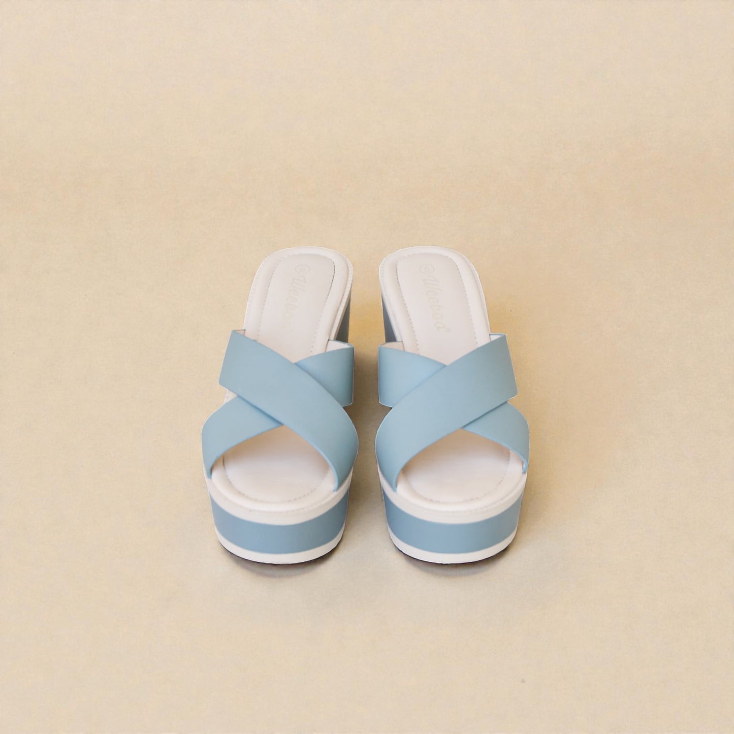 Pair of light blue sandals with white soles on a beige background