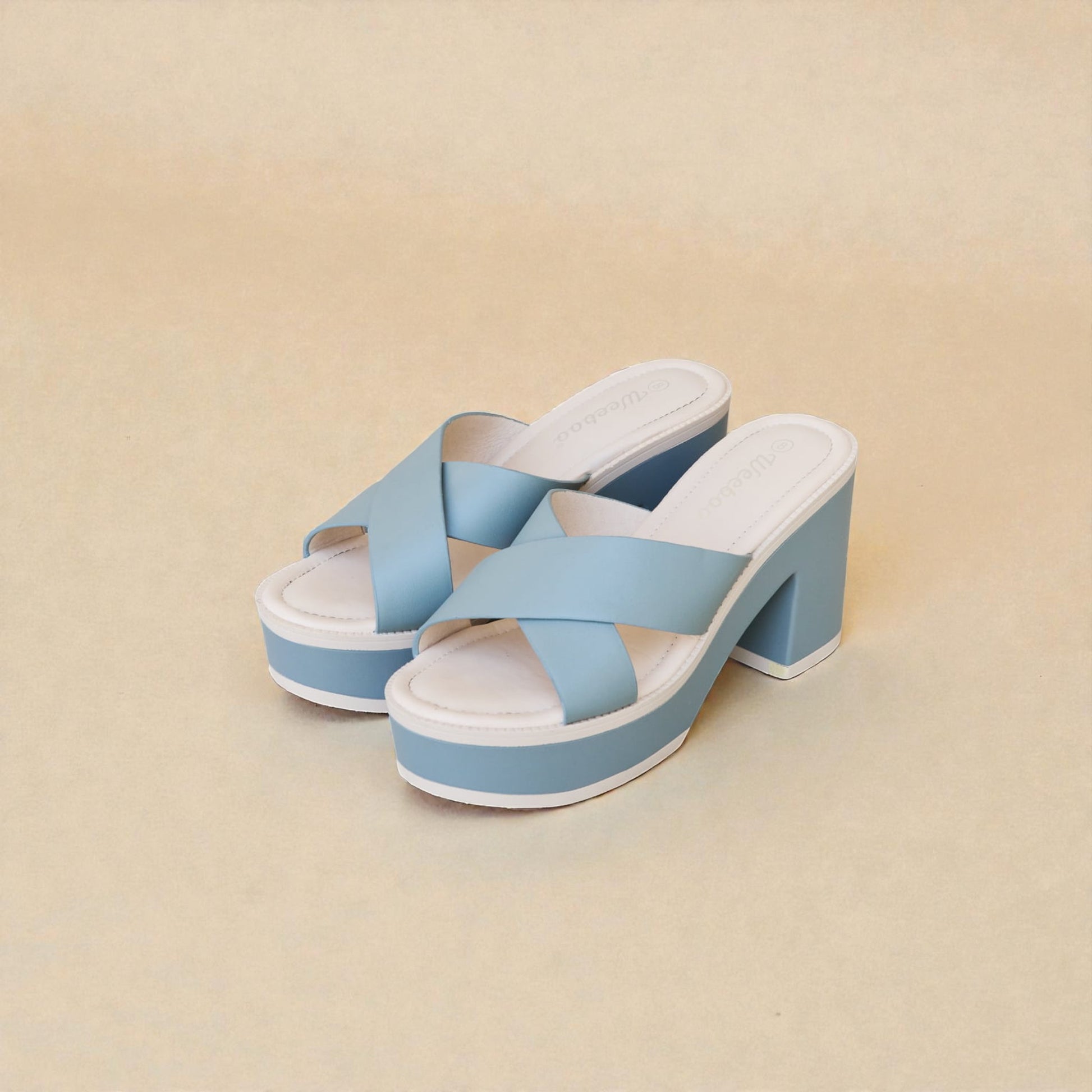 Pair of light blue sandals with white soles on a beige background