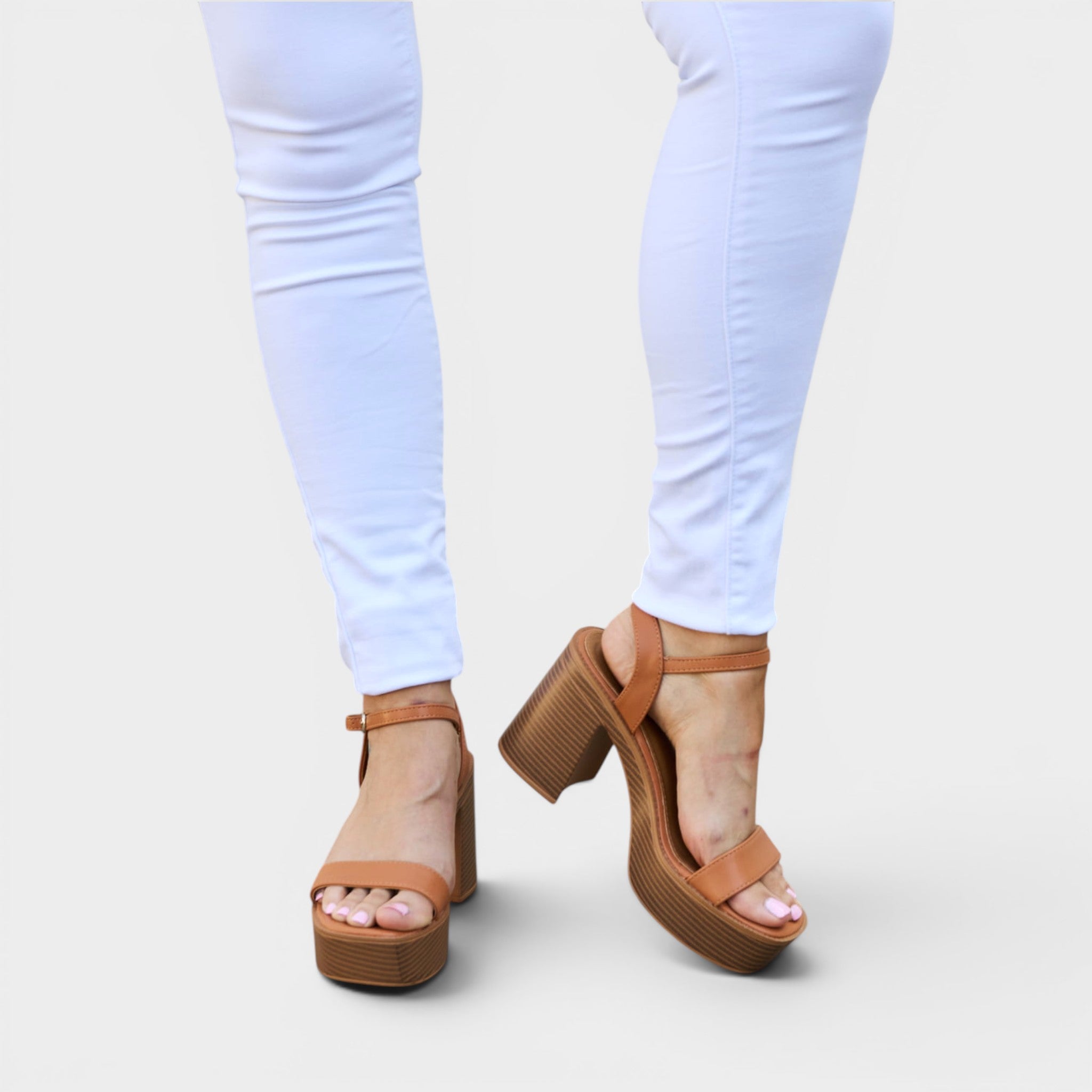 Brown platform sandals worn with light blue jeans on a white background