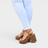 Brown platform sandals worn with light blue jeans on a white background