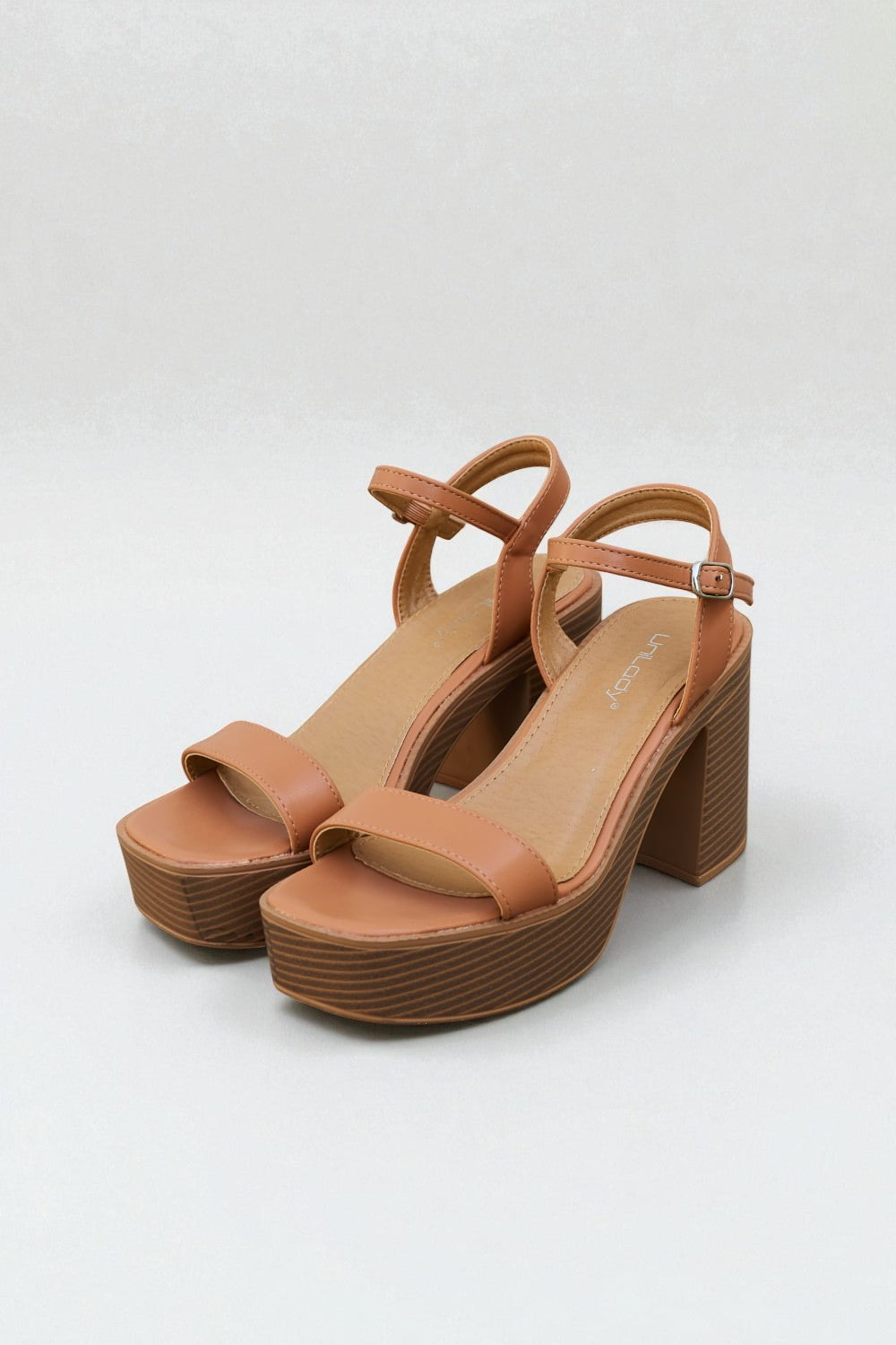 Pair of brown platform sandals on a white background