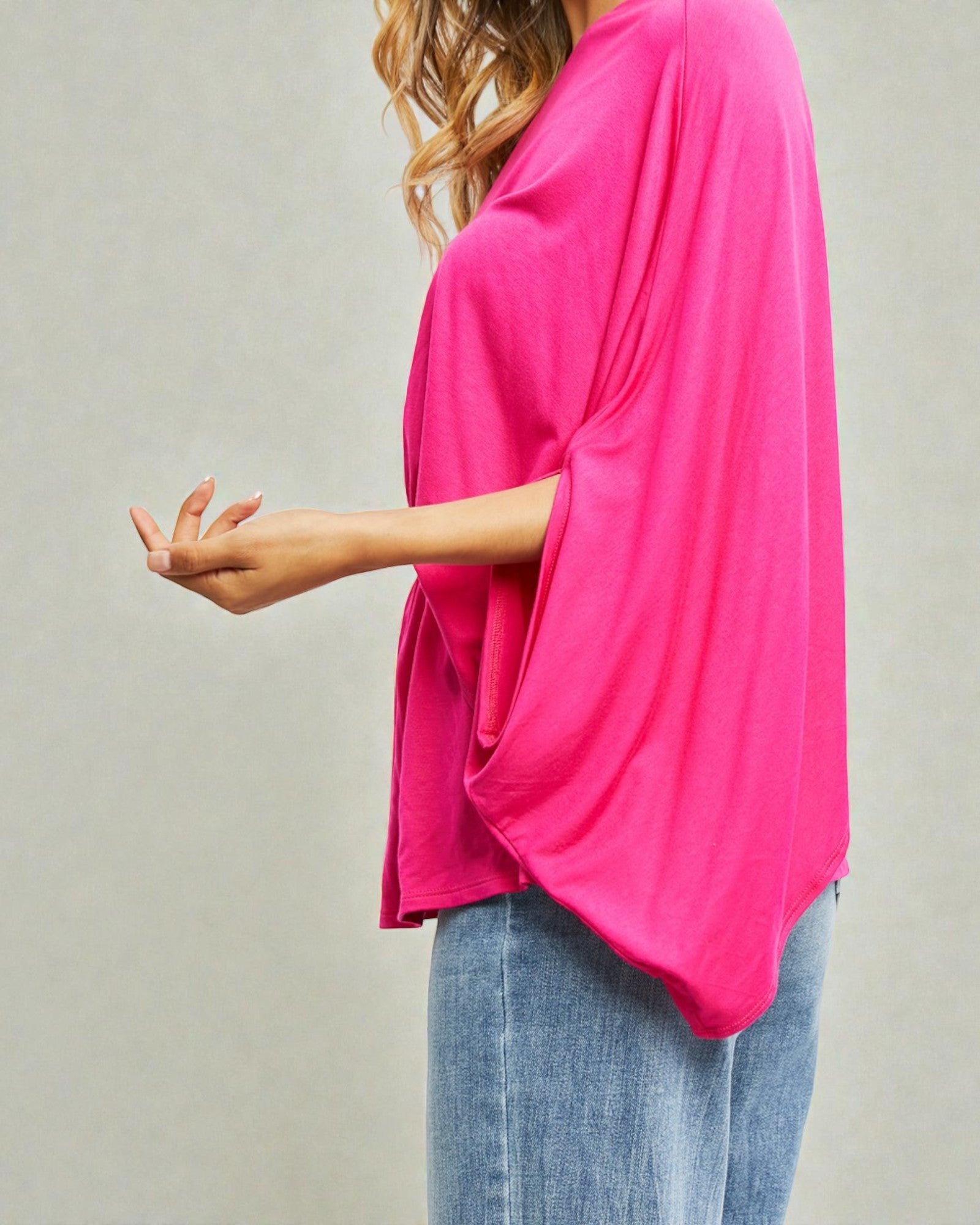 Person wearing a bright pink top and blue jeans on a plain background