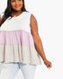 A woman wearing a sleeveless tiered top with a white upper section, a dusty pink middle ruffle, and a light beige lower ruffle, paired with light-wash jeans against a plain white background.