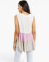 A woman shown from the back wearing a sleeveless tiered tunic top with a white upper section, a light pink middle band, and a light beige lower ruffle, paired with light blue jeans against a white studio background.