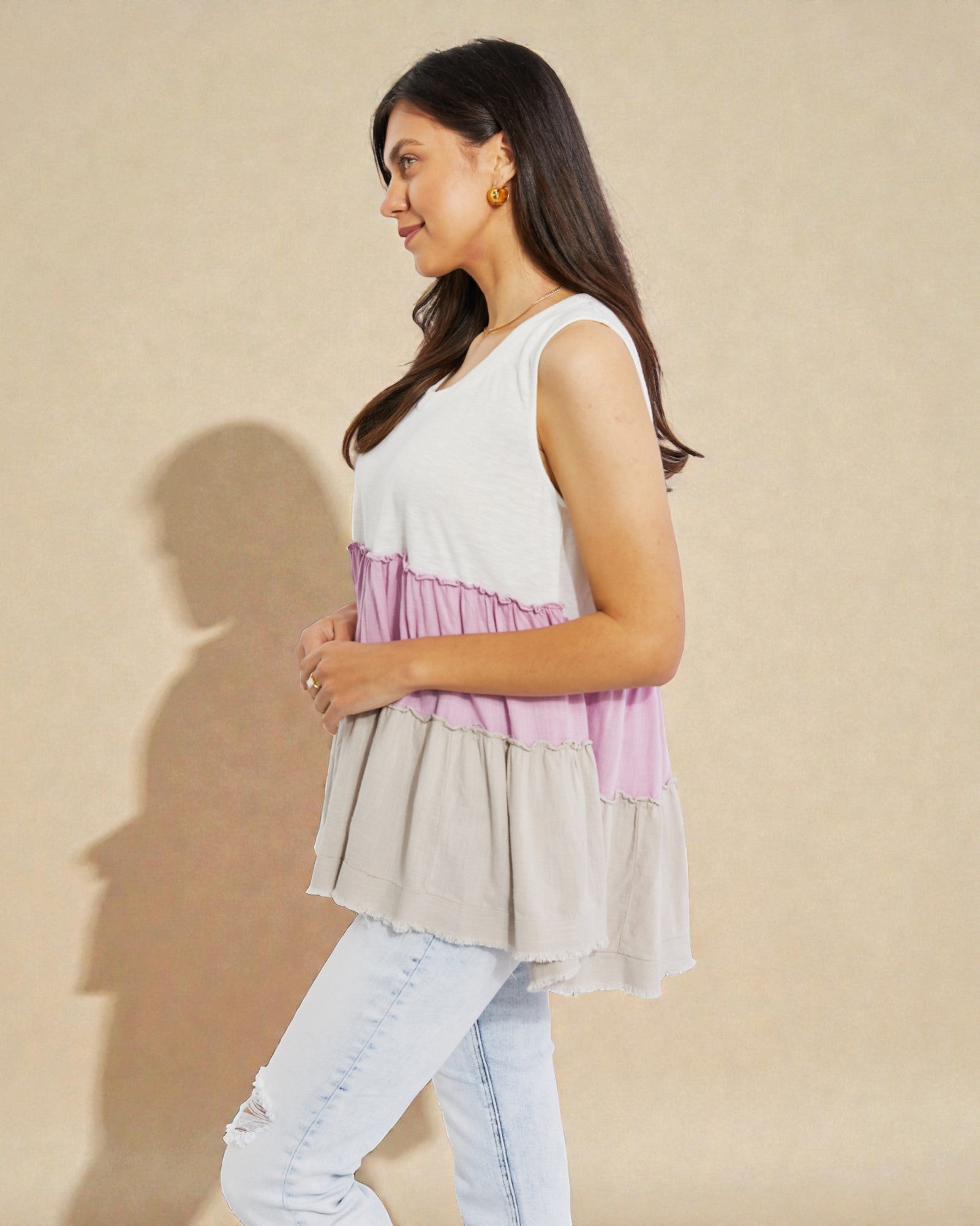 Woman wearing a layered sleeveless top with a beige background