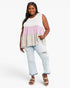 A woman modeling a sleeveless tiered colorblock top with white, light pink, and beige horizontal panels, paired with light-wash distressed jeans and brown wedge sandals against a plain white studio background.