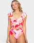 A woman modeling a two-piece swimsuit with a vibrant abstract floral print in pink, orange, and white. The swimsuit features ruffled cap sleeves, a sweetheart neckline with a front cutout and metallic V-shaped accent, and high-waisted bottoms.