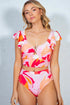 Woman wearing a colorful floral two-piece swimsuit against a gray background